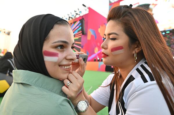 سيدة ترسم ألوان علم قطر على وجه إحدى مشجعات كرة القدم عند وصولهن إلى منطقة المشجعين في هيا لمشاهدة البث المباشر للمباراة الافتتاحية لكأس العالم 2022 بين قطر والإكوادور في لوسيل، شمال الدوحة ، في 20 نوفمبر 2022، قبل بطولة كأس العالم لكرة القدم قطر 2022. - سبوتنيك عربي