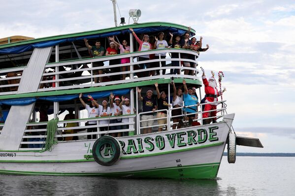 المتطوع خورخي باروسو، مرتديًا زي بابا نويل، يقرع جرسه أثناء وقوفه على متن قارب يبحر في نهر نيغرو لتقديم الهدايا للأطفال في مجتمع إيراندوبا الواقع على ضفاف النهر في مدينة ماناوس بالبرازيل، 17 ديسمبر 2022. منذ عام 1998، تقوم مجموعة تسمى (Amigos do Papai Noel)، وتعني باللغة البرتغالية &quot;أصدقاء سانتا كلوز&quot; بالترويج لعيد الميلاد ضمن الأطفال في ماناوس في المجتمعات الريفية وعلى ضفاف النهر في غابات الأمازون. - سبوتنيك عربي