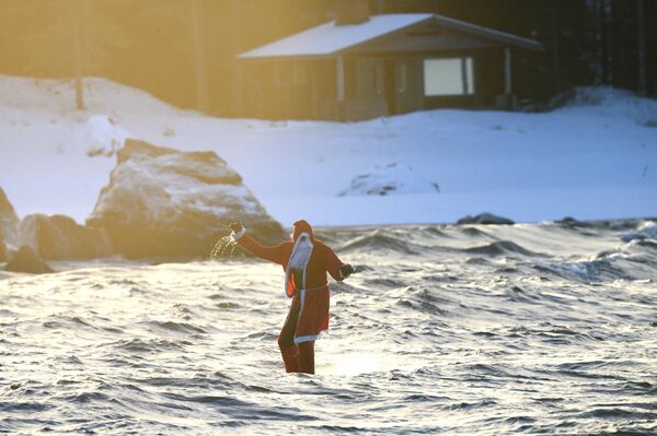 تُظهر هذه الصورة التي التقطت في 6 ديسمبر 2022 رجلاً يرتدي زي بابا نويل يركب لوح تزلج على الماء بالقرب من نيكارليبي، غربي فنلندا. - سبوتنيك عربي