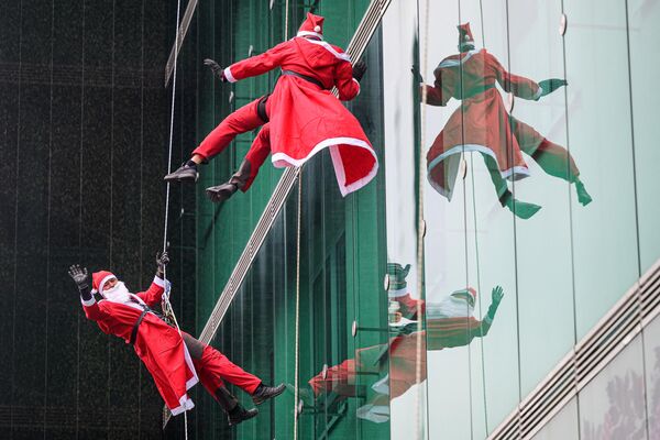متسلقون يرتدون زي بابا نويل يتسلقون مبنى عيادة الأطفال في المركز الطبي لجامعة ليوبليانا في ليوبليانا، سلوفينيا، 19 ديسمبر 2022. - سبوتنيك عربي