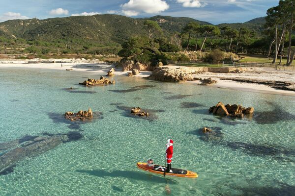 منظر جوي يظهر امرأة ترتدي زي بابا نويل وهي تركب مجدافًا بالقرب من شاطئ ماري إي سول في بيتروسيلا في جزيرة كورسيكا الفرنسية على البحر المتوسط. 20 ديسمبر 2022 - سبوتنيك عربي