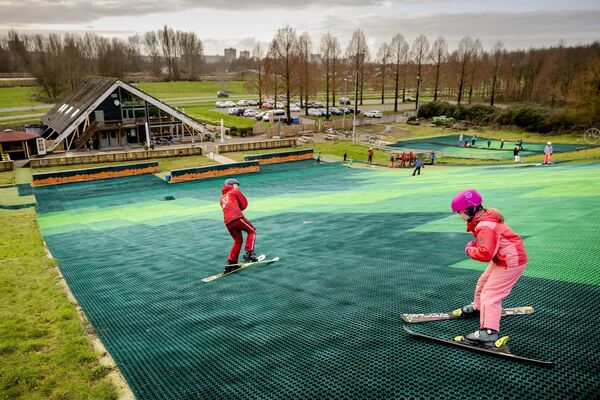يحضر الأطفال فصل تزلج على منحدر تزلج اصطناعي، في ظل عدم وجود ثلوج في العديد من منتجعات التزلج الشهيرة في أوروبا بسبب درجات الحرارة المرتفعة بشكل غير عادي، في بيرخسنهوك، هولندا، 5 يناير 2023. - سبوتنيك عربي