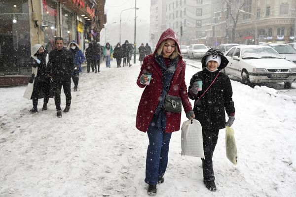 الناس يسيرون خلال تساقط الثلج في شمال طهران، إيران، 15 يناير 2023. - سبوتنيك عربي