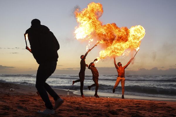 شباب فلسطينيون يظهرون مهاراتهم في التنفس بالنار على طول الشاطئ في مدينة غزة، قطاع غزة، فلسطين 13 يناير 2023. - سبوتنيك عربي