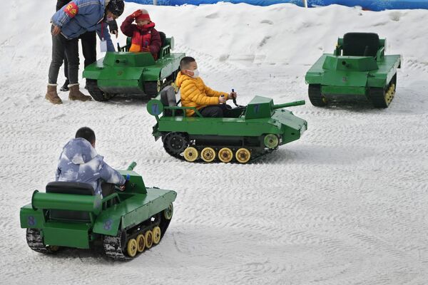 أطفال يركبون دبابات ألعاب في الثلج في حديقة عامة في بكين، الصين 19 يناير 2023. - سبوتنيك عربي