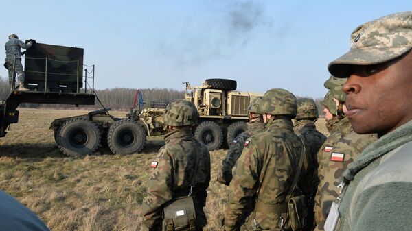 جنود بولنديون يشاهدون القوات الأمريكية أثناء نصب منظومة باتريوت في ميدان اختبار في سوشاشيف في بولندا بتاريخ 21 مارس 2015 - سبوتنيك عربي