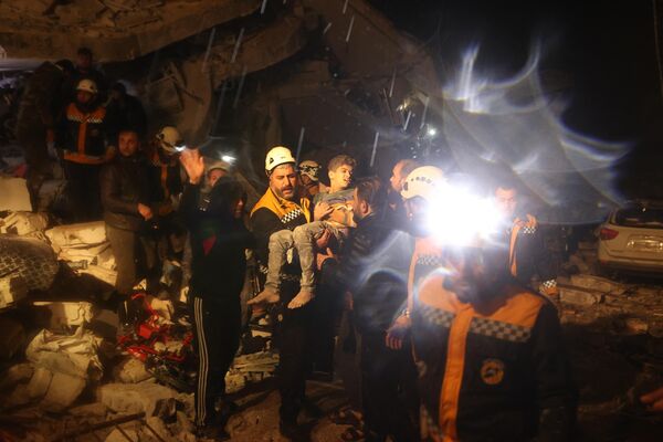 عمال الإنقاذ يحملون طفلاً عثروا عليه من أنقاض أحد المباني بعد زلزال في مدينة ضانا، إدلب السورية، في وقت مبكر من صباح يوم 6 فبراير 2023. - سبوتنيك عربي