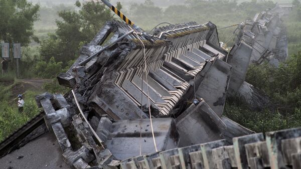 صحفي (يسار) يمر بجوار جسر كاوليا المنهار في مقاطعة هوالين بشرق تايوان في 19 سبتمبر 2022، بعد زلزال قوته 6.9 درجة في 18 سبتمبر. - سبوتنيك عربي