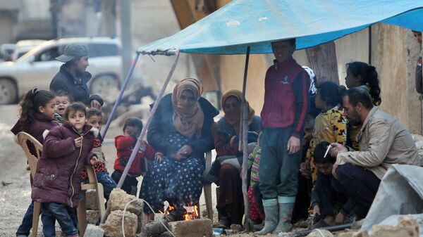 سوريون يسخنون أنفسهم بسبب حريق في بلدة جندريس يوم 7 فبراير 2023 ، مع استمرار عمليات البحث والإنقاذ في أعقاب الزلزال المميت. - سبوتنيك عربي
