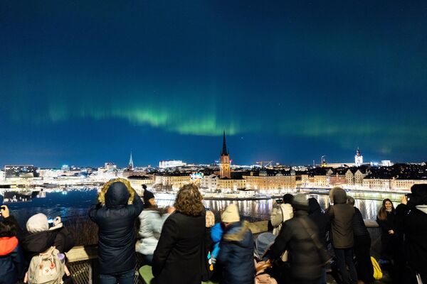 الناس يشاهدون الأضواء الشمالية، الشفق القطبي، في وسط ستوكهولم، في السويد 27 فبراير/شباط 2023. - سبوتنيك عربي