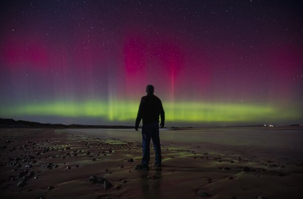 رجل يشاهد الشفق القطبي، المعروف أيضا باسم &quot;الأضواء الشمالية&quot;، في منطقة &quot;تولاغ ستراند&quot;، في مقاطعة دونيجال، آيرلندا - سبوتنيك عربي