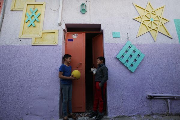 أطفال يلعبون على خلفية منزل عليه رسومات ملونة كجزء من مبادرة لفنان فلسطيني، في حي الزيتون بمدينة غزة، قطاع غزة، فلسطين 12 مارس  2023. - سبوتنيك عربي