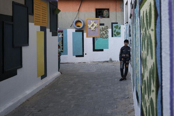 صبي يقف وسط رسومات ملونة كجزء من مبادرة لفنان فلسطيني، في حي الزيتون بمدينة غزة، قطاع غزة، فلسطين 12 مارس  2023. - سبوتنيك عربي