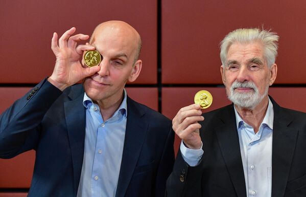 الألمانيان الحائزان على جائزة نوبل في الفيزياء، كلاوس هاسلمان (يمين) وجائزة نوبل في الكيمياء، قائمة بنيامين (يسار) يمزحون ويشكلون مع ميداليات جائزة نوبل بالشوكولاتة بعد حضور ندوة نوبل في السفارة السويدية في برلين ، ألمانيا ، في 7 ديسمبر 2021 . - فاز بنجامين ليست من ألمانيا وديفيد ماكميلان من الولايات المتحدة بجائزة نوبل للكيمياء لعام 2021 لعملهما في تطوير أداة جديدة لتوسيع نطاق التفاعلات الكيميائية بطريقة صديقة للبيئة ، تُعرف باسم &quot;التحفيز العضوي&quot; وكلاوس هاسلمان من ألمانيا ، الولايات المتحدة- فاز العالم الياباني سيوكورو مانابي والإيطالي جورجيو باريزي بجائزة نوبل في الفيزياء لعام 2021 لنماذج المناخ وفهم النظم الفيزيائية. - سبوتنيك عربي