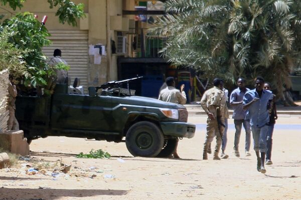 أشخاص يمرون من أمام مركبة عسكرية في الخرطوم في 15 أبريل / نيسان 2023 ، وسط اشتباكات ذكرت في المدينة. - سبوتنيك عربي