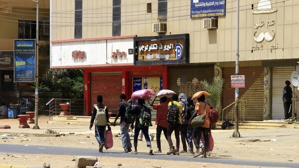 أشخاص يحملون أمتعتهم يسيرون على طول أحد شوارع الخرطوم في 16 أبريل / نيسان 2023 ، مع استمرار القتال بين قوات الجنرالات المتناحرين. - سبوتنيك عربي
