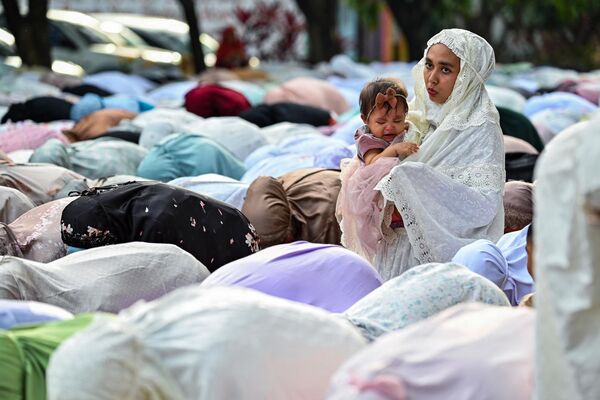 امرأة من المصلين ترعى طفلًا حيث يشارك المسلمون في صلاة الصباح احتفالًا بعيد الفطر، في مجمع الجامعة المحمدية في باندا آتشيه، إندونيسيا في 21 أبريل 2023. - سبوتنيك عربي