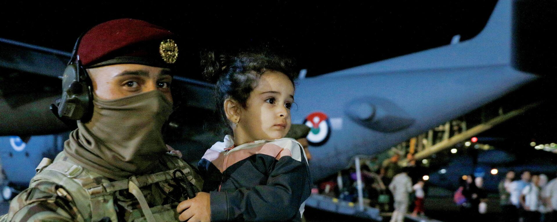 جندي يحمل طفلاً أثناء نزول أشخاص تم إجلاؤهم من السودان من طائرة في مطار عسكري في عمان في 24 أبريل 2023.  - سبوتنيك عربي, 1920, 24.04.2023