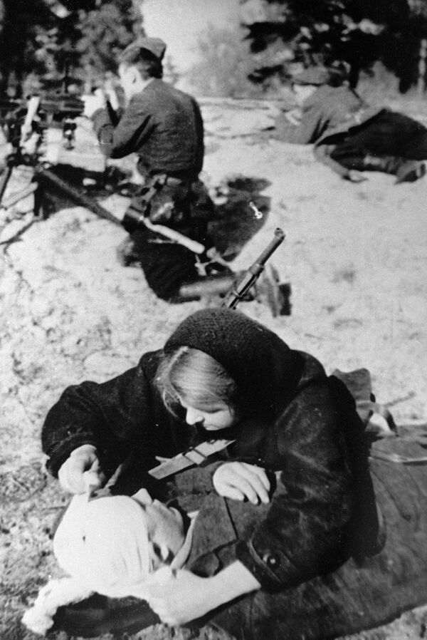 ممرضة في مفرزة المقاومين &quot;باسم غ.إ. كوتوفسكي&quot; تضم الجرحى خلال المعركة. مقاطعة بينسك، بيلاروسيا، 31 مارس/ آذار 1943. - سبوتنيك عربي