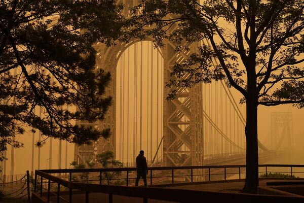 رجل يتحدث على هاتفه وهو ينظر من خلال الضباب الدخاني على جسر جورج واشنطن في فورت لي، نيوجيرسي، 7 يونيو 2023. - سبوتنيك عربي