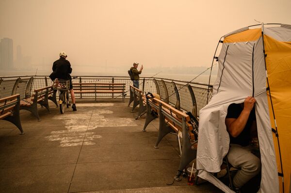 أشخاص يلتقطون صورًا لأفق مانهاتن حيث تسبب الدخان الناجم عن حرائق الغابات في كندا ضبابا دخانيا في مدينة نيويورك، 7 يونيو 2023. - سبوتنيك عربي