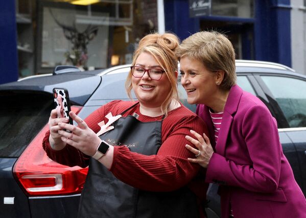 وزيرة اسكتلندا الأولى وزعيمة الحزب الوطني الاسكتلندي، نيكولا ستورجون، تقف لالتقاط صورة سيلفي مع أحد السكان المحليين خلال حملة للانتخابات المحلية، في أربروث اسكتلندا، في 2 مايو 2022. سيذهب المواطن البريطاني إلى صناديق الاقتراع في 5 مايو 2022 لانتخابات الحكم المحلي. - سبوتنيك عربي