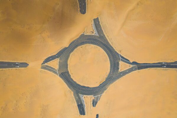 منظر من الأعلى، صورة جوية مذهلة لممر دوار مهجور مغطى بالكثبان الرملية في وسط صحراء دبي أثناء غروب الشمس. دبي، الإمارات العربية المتحدة - سبوتنيك عربي