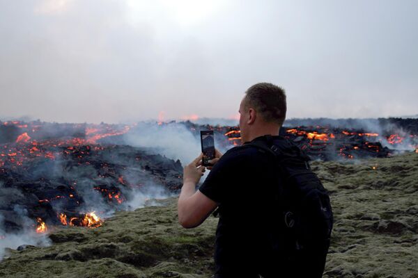 مصور يلتقط صورا للحمم البركانية خلال الثوران البركاني بالقرب من ليتلي هروتور، جنوب غرب ريكيافيك في أيسلندا، 10 يوليو 2023. - سبوتنيك عربي