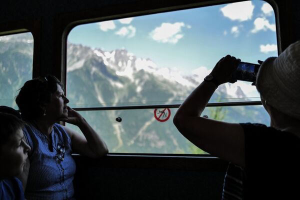 السياح يلتقطون الصور من نافذة قطار مونتنفر الأحمر المتجه إلى بحر الجليد في شاموني مونت بلانك في جبال الألب الفرنسية ، في 11 يوليو 2023. - وطن نيوز العربية