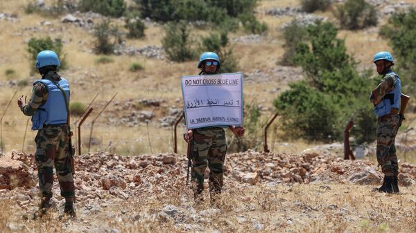 جنود من كتيبة هندية تابعة لقوات الأمم المتحدة المؤقتة في لبنان (اليونيفيل) تحمل لافتة على طول السياج الشائك الذي يحد الحدود بين لبنان (في المقدمة) وإسرائيل (في الخلفية) ، بالقرب من قرية كفرشوبا جنوب لبنان ، 21 يوليو  2023. - سبوتنيك عربي