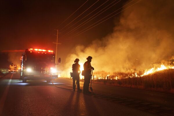 يراقب رجال الإطفاء النيران المشتعلة على طول طريق جيلمان سبرينغز أثناء حريق الأرنب في وقت متأخر من يوم 14 يوليو 2023  في مورينو فالي، ولاية كاليفورنيا الأمريكية. - سبوتنيك عربي