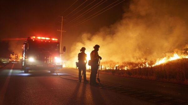 يراقب رجال الإطفاء النيران المشتعلة على طول طريق جيلمان سبرينغز أثناء حريق الأرنب في وقت متأخر من يوم 14 يوليو 2023  في مورينو فالي، ولاية كاليفورنيا الأمركية. - سبوتنيك عربي