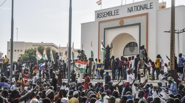 الوضع في النيجر -أنصار يلوحون بالأعلام النيجيرية أثناء احتشادهم لدعم المجلس العسكري النيجيري أمام مبنى الجمعية الوطنية في نيامي - سبوتنيك عربي
