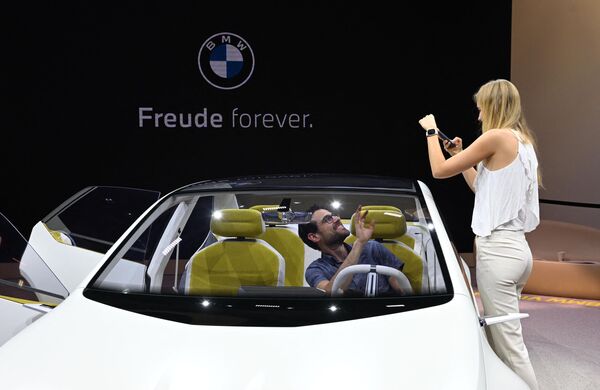 امرأة تلتقط صوراً لرجل يجلس في سيارة Vision Neue Klasse (الفئة الجديدة) من قبل شركة صناعة السيارات الألمانية BMW في معرض ألمانيا الدولي للسيارات في ميونيخ، 4 سبتمبر 2023. - سبوتنيك عربي