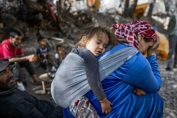 أم تحمل طفلها على ظهرها ترقد مع آخرين خارج منزلهم الذي تضرر من الزلزال في تيجيخت، في سلسلة جبال أطلس، في 14 سبتمبر 2023. - سبوتنيك عربي