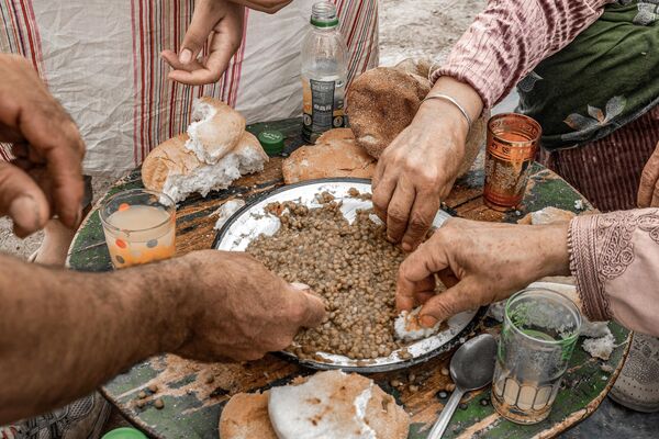 الناجون من الزلزال النازحون يتشاركون وجبة العدس لتناول طعام الغداء في خيمتهم في قرية بالقرب من أمزميز في 13 سبتمبر 2023.  - سبوتنيك عربي