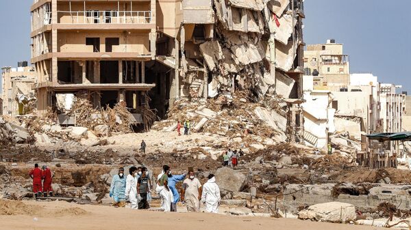 Люди рядом с разрушенным районом в городе Дерна, Ливия - سبوتنيك عربي