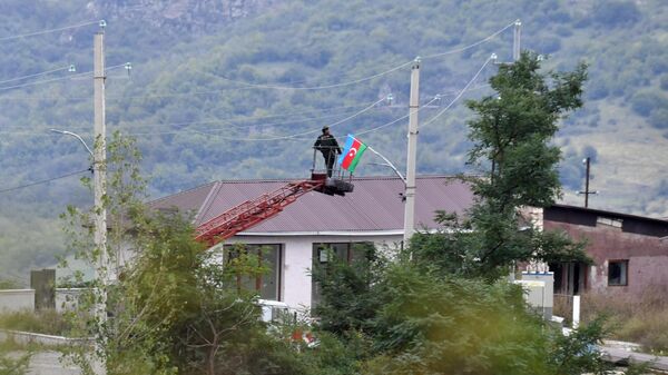 الوضع في قره باغ - رجل يرفع علم أذربيجان على سطح منزل في أحد الأحياء السكنية في قره باغ - سبوتنيك عربي