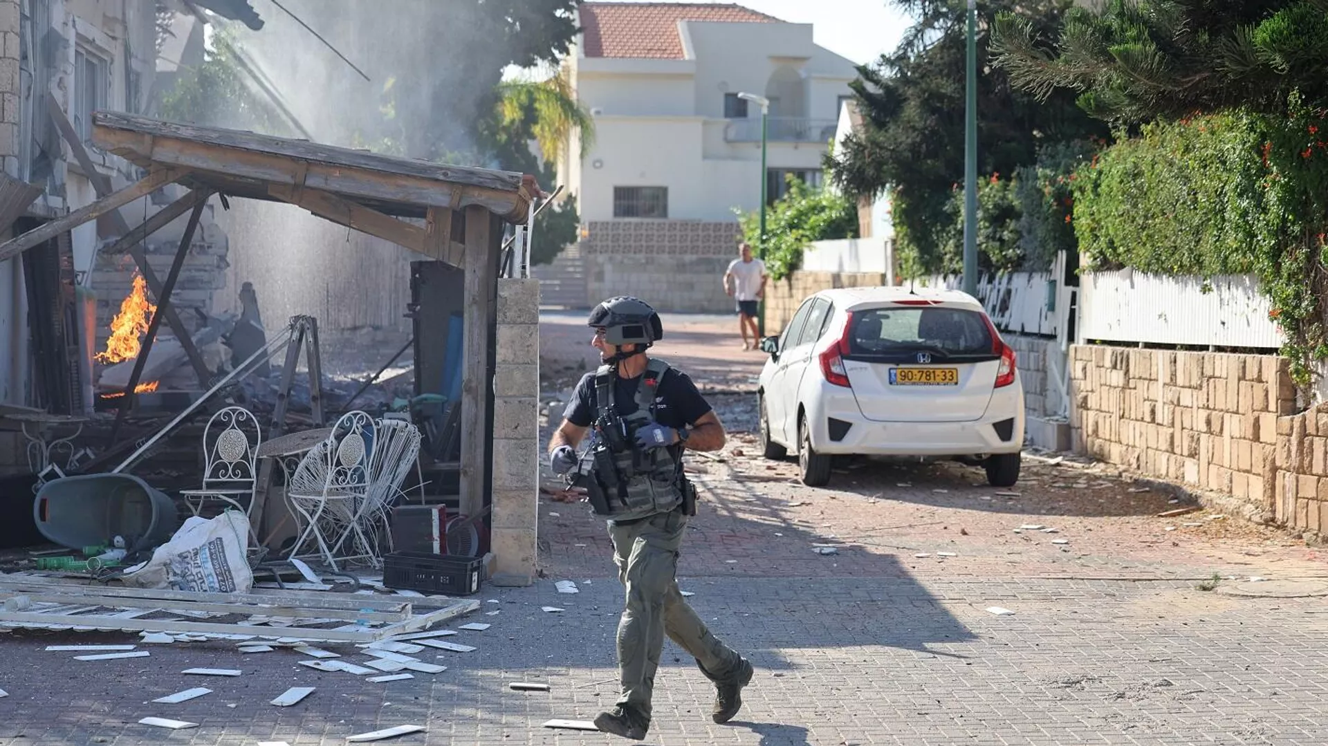 أحد أفراد القوات الإسرائيلية يمر أمام حريق مشتعل في منزل في عسقلان، في أعقاب هجوم صاروخي من قطاع غزة على جنوب إسرائيل، 7 أكتوبر/ تشرين الأول 2023 - سبوتنيك عربي, 1920, 07.10.2023