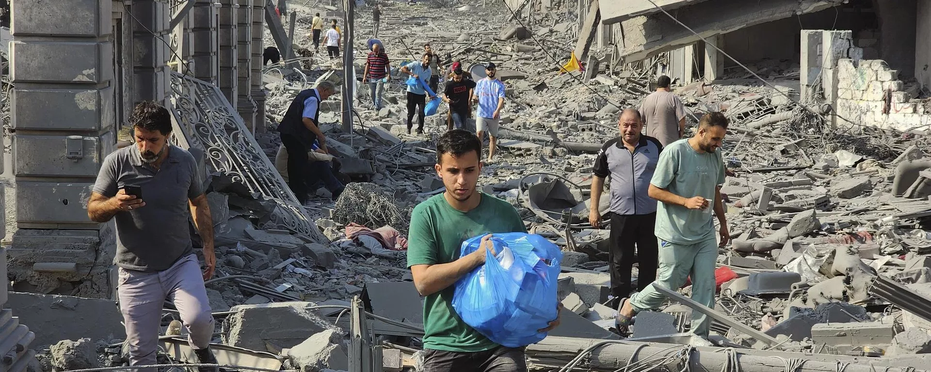 فلسطينيون يسيرون بين أنقاض المباني التي دمرتها الغارات الجوية الإسرائيلية في غزة، 10 أكتوبر/ تشرين الأول 2023 - سبوتنيك عربي, 1920, 29.10.2023