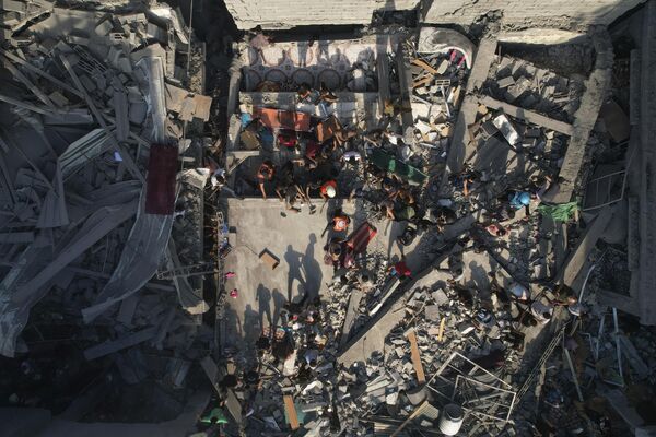 فلسطينيون يتفقدون أنقاض المباني التي ضربتها غارة جوية إسرائيلية في مخيم الشاطئ للاجئين، قطاع غزة، 12 أكتوبر 2023. - سبوتنيك عربي
