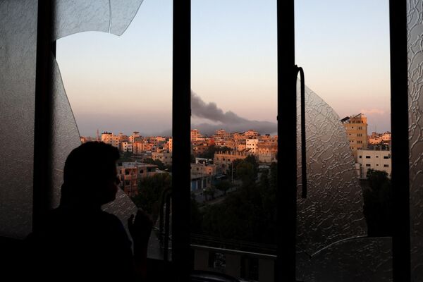طفل فلسطيني يشاهد الدخان يتصاعد في الأفق بعد غارة جوية إسرائيلية على مدينة غزة، قطاع غزة، 13 أكتوبر 2023. - سبوتنيك عربي