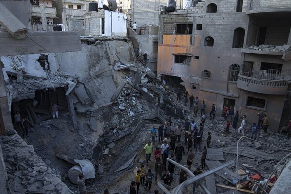 فلسطينيون يبحثون عن ناجين من مبنى دمره القصف الإسرائيلي في خان يونس في قطاع غزة، 19 أكتوبر 2023. - سبوتنيك عربي