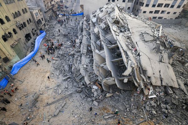 أشخاص يتفقدون أنقاض مبنى دمر جراء غارات إسرائيلية في مدينة غزة، قطاع غزة 8 أكتوبر 2023. - سبوتنيك عربي