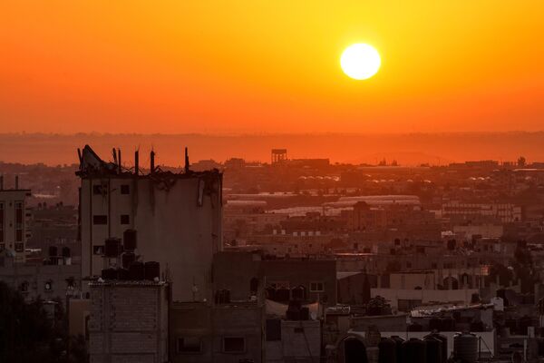 شروق الشمس على خلفية مبنى متضرر في أفق خان يونس في جنوب قطاع غزة، 19 أكتوبر 2023. - سبوتنيك عربي