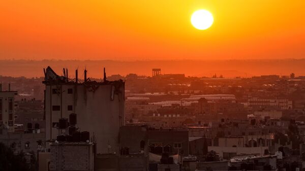 شروق الشمس على خلفية مبنى متضرر في أفق خان يونس في جنوب قطاع غزة، 19 أكتوبر 2023. - سبوتنيك عربي