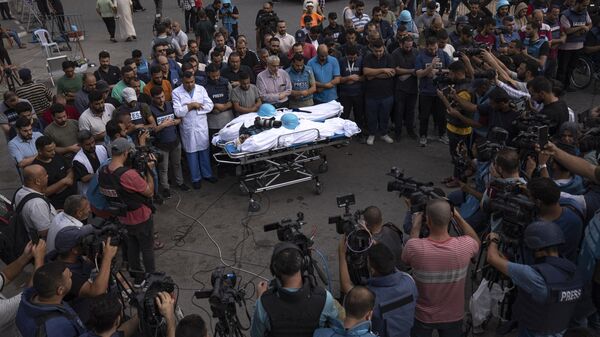 فلسطينيون، معظمهم من الصحفيين، يتجمعون حول جثتي الصحفيين الفلسطينيين، محمد صبح وسعيد الطويل، اللذين قُتلا في غارة جوية إسرائيلية في مدينة غزة، الثلاثاء، 10 أكتوبر 2023. - سبوتنيك عربي