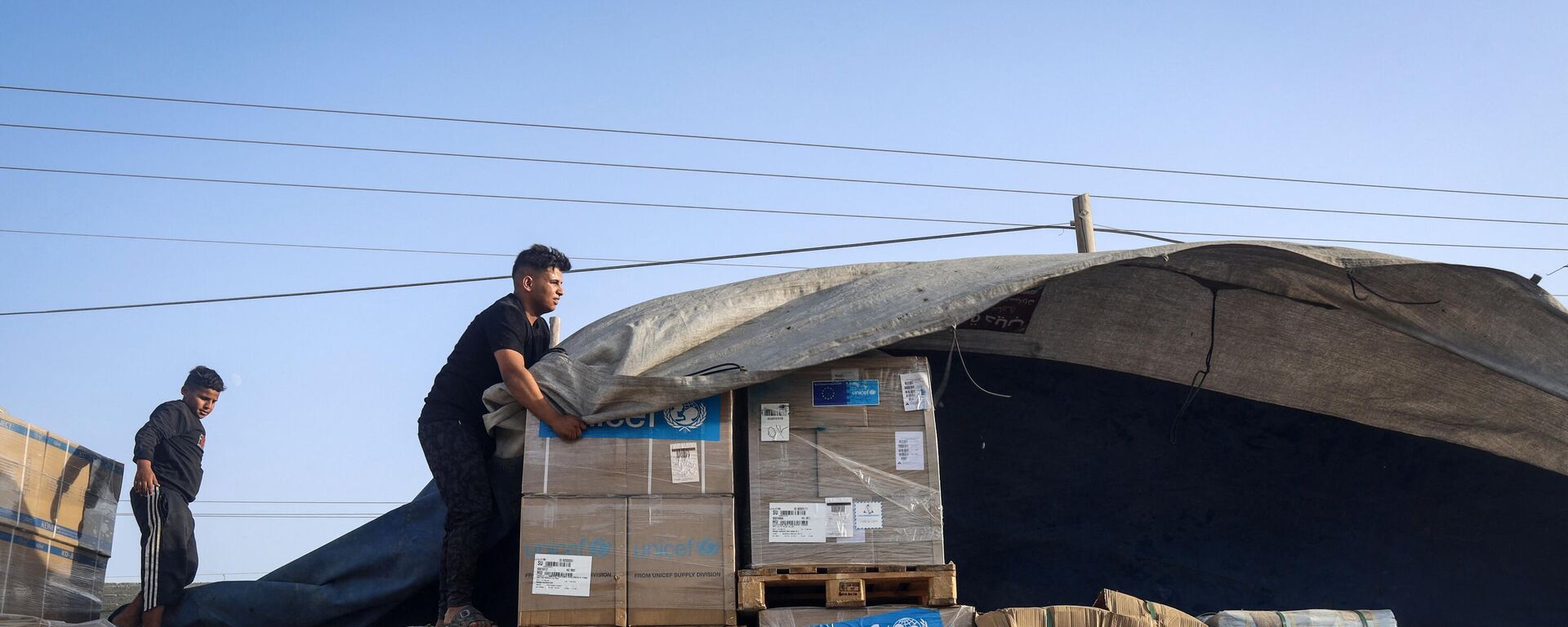رجل يفرغ مساعدات إنسانية على قافلة شاحنات تدخل قطاع غزة من مصر عبر معبر رفح الحدودي في 21 أكتوبر 2023 - سبوتنيك عربي, 1920, 01.03.2024