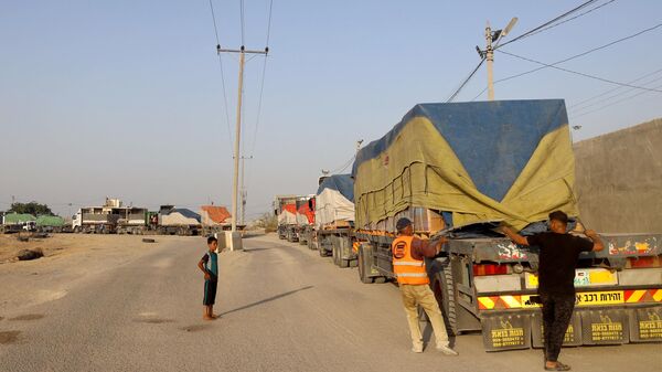 أشخاص يفرغون مساعدات إنسانية على قافلة شاحنات تدخل قطاع غزة من مصر عبر معبر رفح الحدودي في 21 أكتوبر 2023. - سبوتنيك عربي