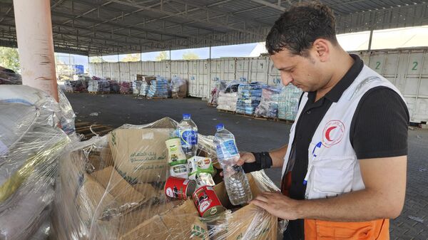 يقوم عمال الأمم المتحدة والهلال الأحمر بإعداد المساعدات للتوزيع على الفلسطينيين في مستودع الأونروا في دير البلح بقطاع غزة يوم الاثنين 23 أكتوبر 2023. - سبوتنيك عربي